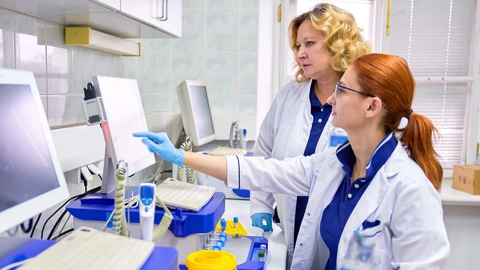 Специалисты в белых халатах работают с оборудованием медицинской лаборатории